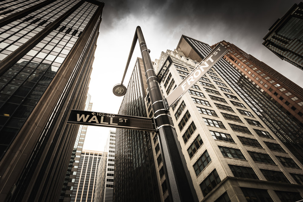 Photo of Wall Street skyline with street sign.
